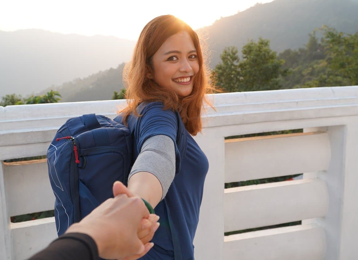 Syifa Adriana smiling with her arm outstretched towards camera holding someone's hand